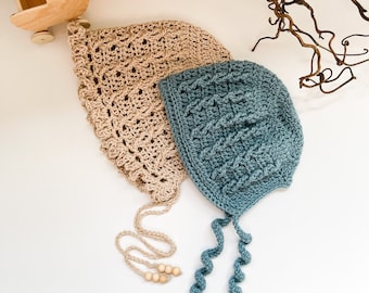 May include: Two crocheted baby bonnets, one in beige and one in teal blue, with wooden bead ties. The bonnets are laid out on a white surface.