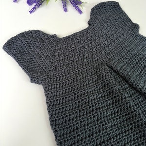 May include: A gray crocheted top with short sleeves and a scoop neck.