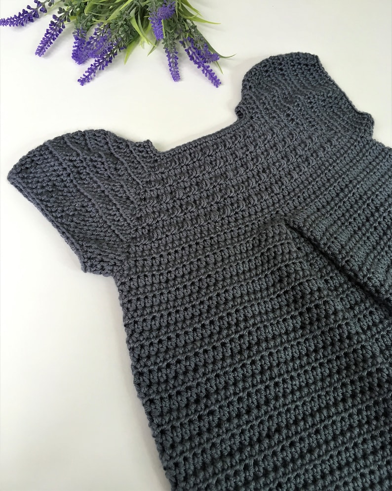 May include: A gray crocheted top with short sleeves and a scoop neck.