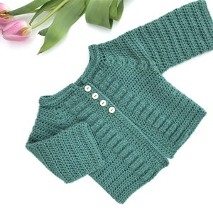 May include: A teal crocheted baby cardigan with button closures.