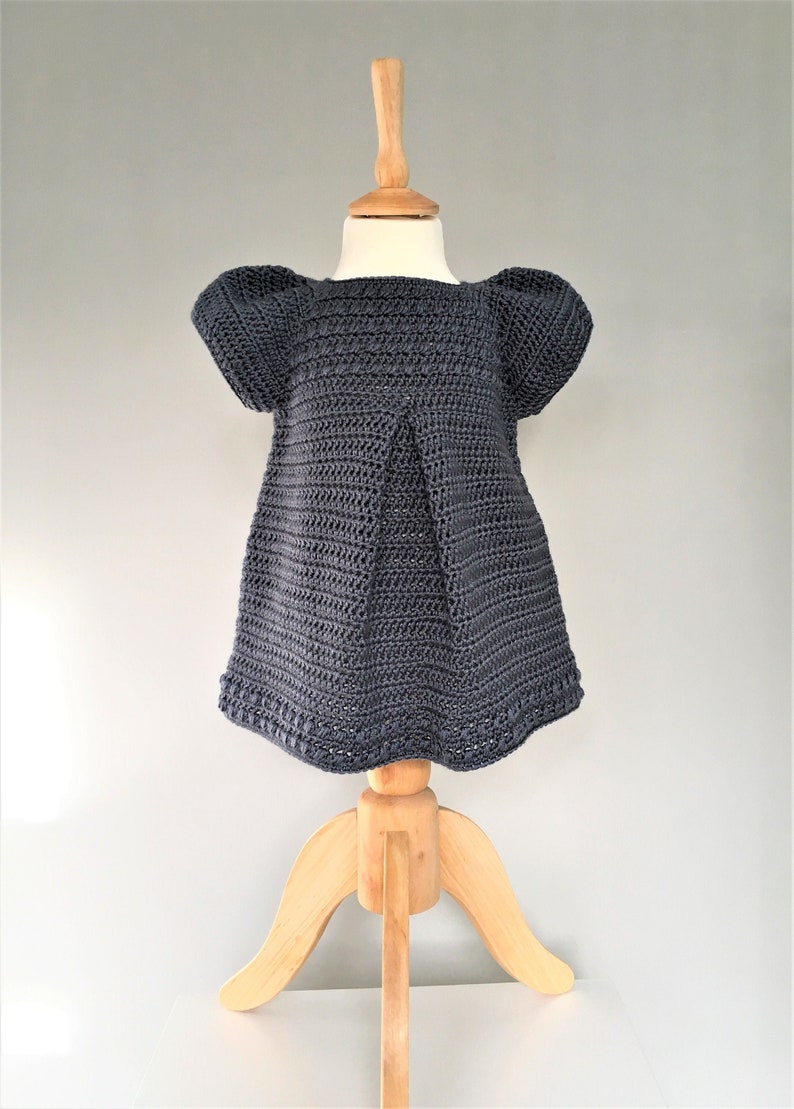 May include: A dark gray crocheted dress with puffed sleeves on a wooden dress form.
