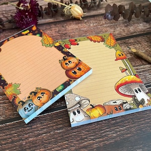 Könnte beinhalten: Zwei Notizblöcke im Herbst-Design mit liniertem Papier. Ein Notizblock hat einen Rand aus Kürbissen, Blättern und Pilzen. Der andere Notizblock hat einen Rand aus Pilzen, Blättern und Kürbissen. Beide Notizblöcke haben einen hellbraunen Hintergrund.