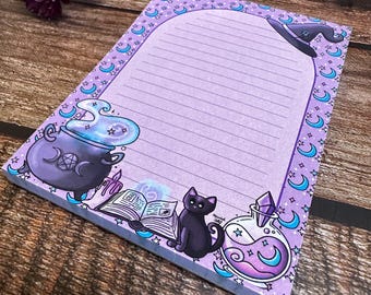 May include: A lined lavender notepad with a witchy theme. The notepad features illustrations of a cauldron, a black cat, a potion bottle, and a witch's hat. The border is decorated with crescent moons and stars.