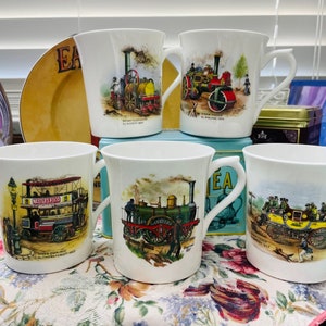 May include: Set of five white ceramic teacups with colorful illustrations of vintage vehicles. The illustrations include a steam engine, a horse-drawn carriage, and a double-decker bus. The text on the cups reads "Nestle's Food" and "The Centenary 1911".