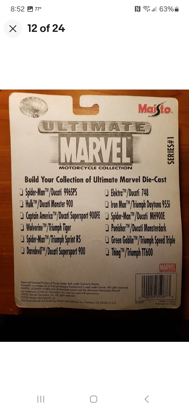 Op de afbeelding: Een witte kaart met een zwart en rood logo voor Maisto's Ultimate Marvel Motorcycle Collection. De kaart vermeldt de verschillende Marvel-personages en motorfietsen die in de collectie zijn opgenomen. De tekst op de kaart luidt "Build Your Collection of Ultimate Marvel Die-Cast".