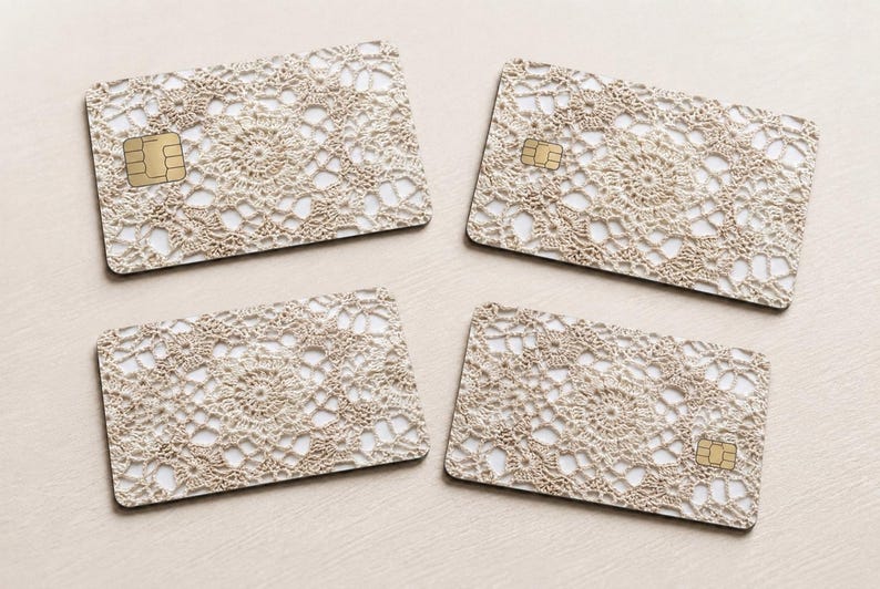 Pode incluir: Quatro cart&otilde;es retangulares com um padr&atilde;o de renda de croch&ecirc; bege. Cada cart&atilde;o tem um chip dourado no lado esquerdo. Os cart&otilde;es est&atilde;o dispostos em uma superf&iacute;cie bege clara.