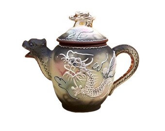 Op de afbeelding: Een klein, bruin aardewerken theepot met een drakenontwerp. De theepot heeft een deksel met een drakenknop en een handvat aan de zijkant.