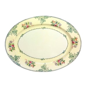 Può includere: Un piatto da portata ovale bianco con un design floreale verde e oro. Il piatto ha un bordo rialzato e una superficie liscia.