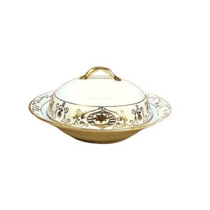 Può includere: Un piatto da portata in ceramica bianca con un bordo dorato e intricati disegni floreali dorati. Il piatto ha un coperchio con un manico dorato.