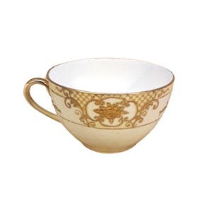 Puede incluir: Una taza de té blanca con un diseño floral dorado alrededor del borde. La taza está hecha de porcelana y tiene un aspecto delicado y femenino.