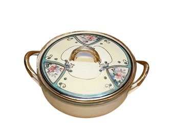 May include: A white porcelain serving dish with a lid. The lid has a gold rim and a floral design in shades of pink, blue, and green. The dish has two handles.