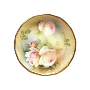 May include: A white porcelain plate with a gold rim features a hand-painted design of pink and white roses with green leaves.