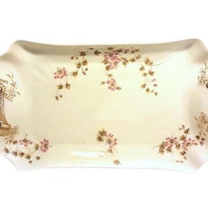 May include: A white ceramic serving tray with gold handles and a floral design. The tray has a scalloped edge and features a delicate pattern of pink flowers and green leaves.
