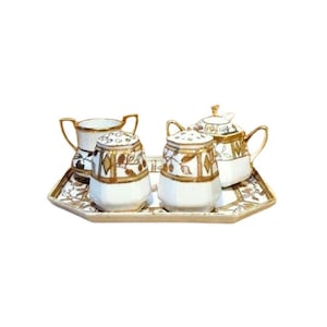 Może przedstawiać: Zestaw do herbaty z porcelany w stylu vintage z tacą. Zestaw zawiera cukiernicę, dwie solniczki i imbryk. Elementy są białe ze złotymi wykończeniami i wzorem liści. Taca jest prostokątna ze złotą obwódką.