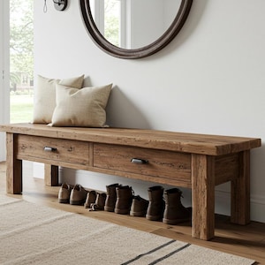 May include: A rectangular wooden bench with a natural brown finish, featuring two drawers with dark metal handles. The bench has four sturdy legs and an open storage space underneath, currently holding several pairs of brown leather boots.