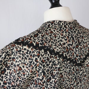 Puede incluir: Una blusa sin mangas con estampado de leopardo y ribete de encaje negro alrededor del escote.
