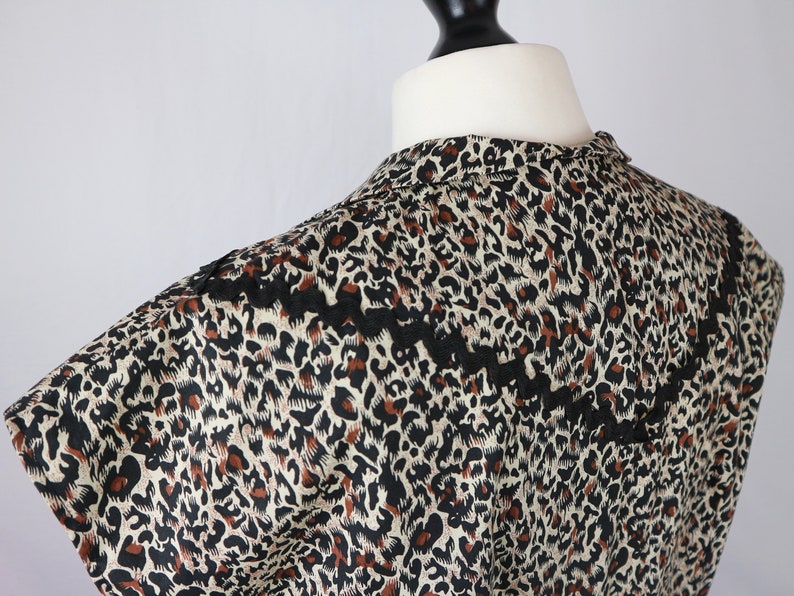 Puede incluir: Una blusa sin mangas con estampado de leopardo y ribete de encaje negro alrededor del escote.