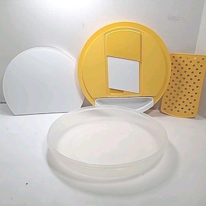 Puede incluir: Un conjunto de accesorios de cocina en blanco y amarillo. Incluye una tapa blanca semicircular, una tapa circular amarilla con una abertura rectangular, un rectángulo perforado amarillo y un recipiente transparente de forma ovalada.