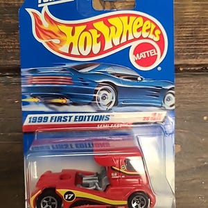 May include: A red and yellow Hot Wheels Semi Fast truck toy car in its original packaging. The packaging is blue with the Hot Wheels logo and text that reads "GUARANTEED FOR LIFE" and "1999 FIRST EDITIONS". The toy car has the number 17 on the side.