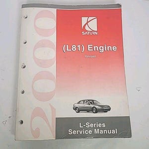 Peut inclure: Manuel de service Saturn L-Series 2000. La couverture blanche avec un panneau rouge présente le logo Saturn, le texte "(L81) Engine Revised" et une illustration d'une berline argentée. Le manuel est relié avec trois trous.