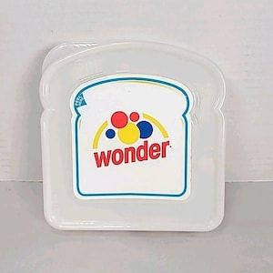 May include: A clear plastic sandwich container shaped like a slice of bread. The container has a white label with the word "wonder" in red, and a design of red, yellow, and blue circles.