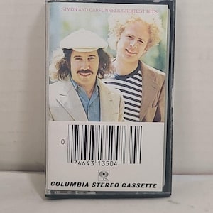 May include: A vintage cassette tape of Simon & Garfunkel's Greatest Hits. The cover features a photo of the duo. The cassette case is black, with a white label that includes a barcode and the text "COLUMBIA STEREO CASSETTE".