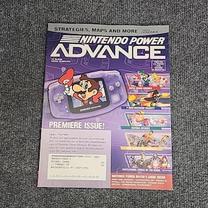 May include: A Nintendo Power Advance magazine with a purple cover featuring Mario and a Game Boy Advance. The magazine includes game titles like Super Mario Advance and Castlevania: Circle of the Moon. The magazine is a premiere issue.