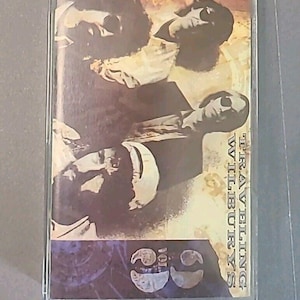 May include: A cassette tape with a faded image of four men in sunglasses. The text "TRAVELING WILBURYS VOL. 1" is printed on the right side of the tape.