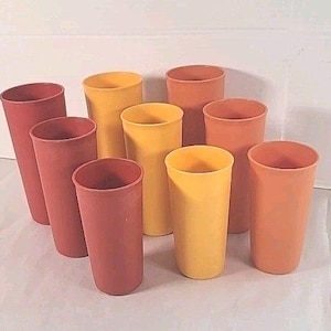 Puede incluir: Una colección de diez vasos altos y cilíndricos en tonos rojos, amarillos y naranjas. Los vasos están dispuestos en grupo, mostrando sus variados colores y formas. Los vasos son de un material sólido.