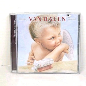May include: A CD case featuring the album cover for Van Halen. The artwork depicts a cherubic figure with a cigarette, angel wings, and the band's name in red. The case also includes the text "Warner Remasters".