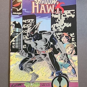 May include: A comic book cover for "Shadow Hawk" features a futuristic armored figure with a cityscape backdrop. The cover includes the text "EXTRA! SPAWN" and "LURKS WITHIN THESE PAGES!" along with the price.