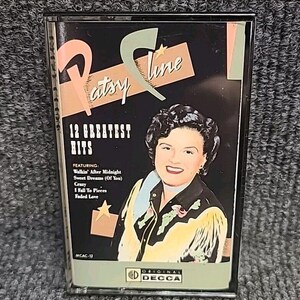 May include: A cassette tape case featuring a portrait of Patsy Cline with the title "12 Greatest Hits" and a list of songs including "Walkin' After Midnight", "Sweet Dreams (Of You)", "Crazy", "I Fall To Pieces", and "Faded Love". The case is red, white, and black with a gold star and the Decca Records logo.