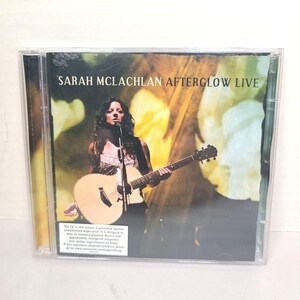 Op de afbeelding: Een cd-hoesje met het album "Afterglow Live" van Sarah McLachlan. De cover toont McLachlan die een akoestische gitaar bespeelt en in een microfoon zingt. De achtergrond heeft een geel-groen kleurenschema.