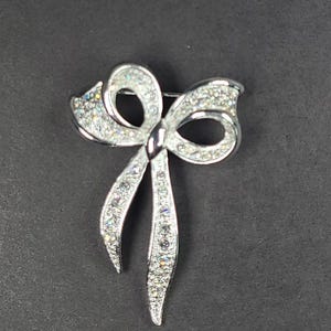 Broche de lazo con diamantes de imitación de cristal transparente en tono plateado de Napier