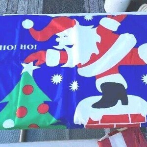 Op de afbeelding: Een blauwe kerstbanner met een cartoonontwerp van de kerstman. De kerstman draagt een rood pak en hoed, met witte randen, en komt uit een schoorsteen. Een groene kerstboom met rode ornamenten en witte sterren zijn ook te zien. De woorden "HO! HO! HO!" staan op de banner.