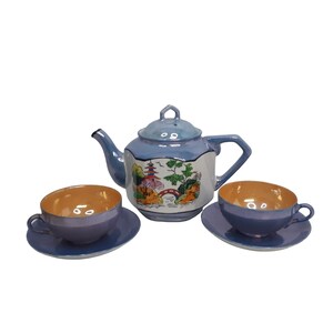 May include: A blue and white porcelain tea set with a Japanese-inspired design. The teapot and cups feature a landscape scene with a bridge, trees, and a pagoda. The set is in excellent condition.