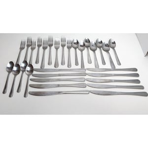 May include: A stainless steel flatware set consisting of multiple forks, spoons, and knives arranged in rows. The collection includes various sizes of spoons and forks, along with several matching dinner knives, all featuring a simple, polished metallic finish.