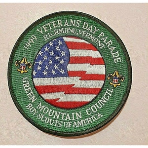 Könnte beinhalten: Grün-weißer gestickter Aufnäher mit dem Text "2009 Veterans Day Parade Green Mountain Council Boy Scouts of America Richmond, Vermont". Der Aufnäher zeigt in der Mitte eine rot-weiß-blaue amerikanische Flagge.