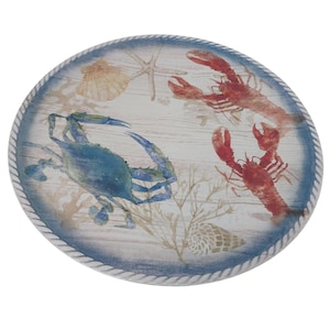May include: Round decorative serving tray with a nautical theme. The tray features a blue crab, red lobsters, seashells, and starfish on a light wood-grain background. The edge is trimmed with a blue rope design.