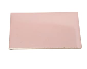 May include: A rectangular, light pink tile with a smooth surface. The tile has a slightly off-white edge, suggesting it may be a ceramic or similar material. The overall shape is a simple rectangle.
