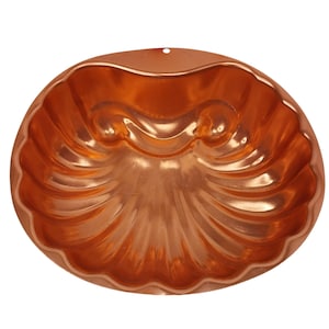 May include: A copper-colored, shell-shaped mold with a scalloped edge and a small hole at the top. The interior features a detailed, textured design. This vintage kitchenware item is ideal for baking decorative cakes or desserts.