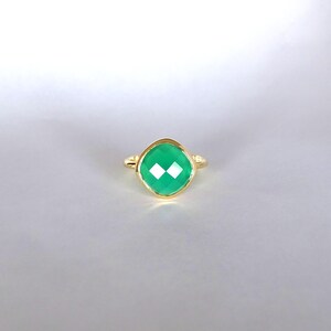 Puede incluir: Un anillo de oro con una piedra preciosa verde. La piedra preciosa es de talla coj&iacute;n y tiene un dise&ntilde;o facetado.