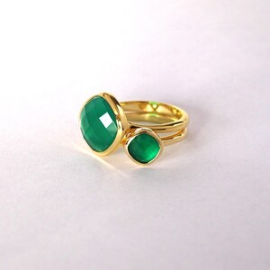 Puede incluir: Un anillo de oro con dos engastes de piedras preciosas verdes. La piedra m&aacute;s grande es de forma cuadrada y la m&aacute;s peque&ntilde;a es redonda.