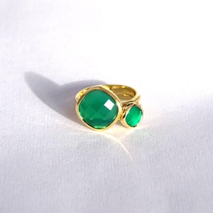 Puede incluir: Un anillo de oro con dos engastes de piedras preciosas verdes. La piedra m&aacute;s grande es de forma cuadrada, mientras que la m&aacute;s peque&ntilde;a es redonda.