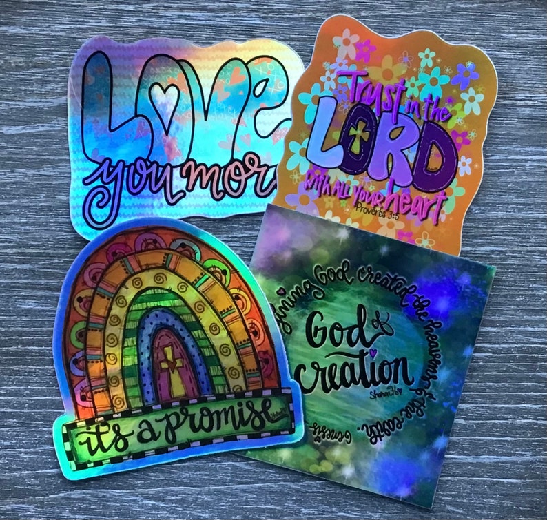 May include: Four iridescent stickers with religious themes. The first sticker is a rainbow with the text "it's a promise". The second sticker has a heart with the text "Love you more". The third sticker has a heart with the text "Trust in the Lord with all your heart" and the scripture reference "Proverbs 3:5". The fourth sticker has a galaxy background with the text "Honing God creator of the heavens and the earth" and "God & Creation".