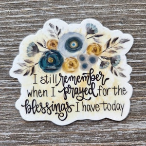 May include: A white sticker with a watercolor floral design in shades of blue, gray, and yellow. The sticker features the text "I still remember when I prayed for the blessings I have today."