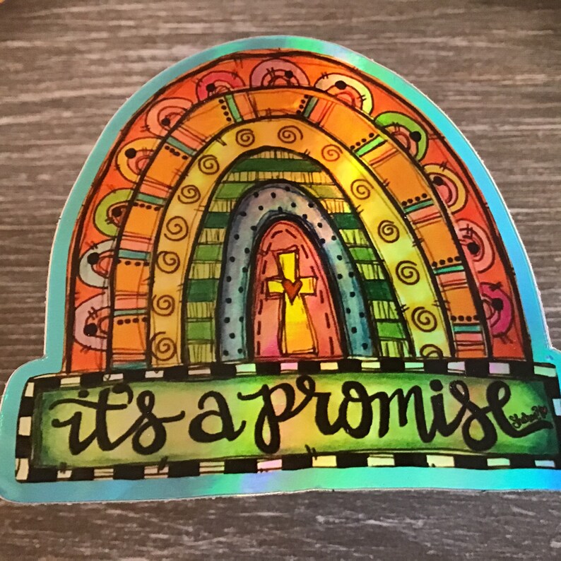 May include: A colorful rainbow sticker with a cross and heart in the center arch. The sticker has a blue border and the text "it's a promise" in black cursive lettering.