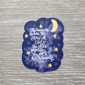 May include: A blue and white sticker with a crescent moon and stars. The sticker features the text "The heavens declare the glory of God the skies proclaim the work of His hands Psalm 19:1".