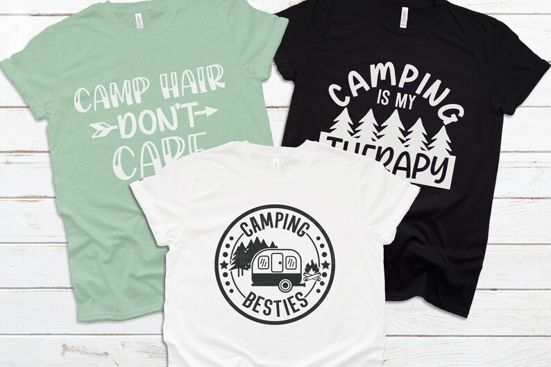 May include: Three t-shirts with camping-themed designs. The first shirt is light green with the text "Camp Hair Don't Care". The second shirt is black with the text "Camping is my Therapy". The third shirt is white with a black and white graphic of a camper and the text "Camping Besties".