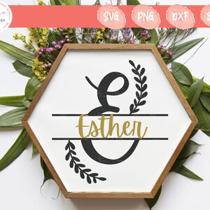 May include: A hexagonal wooden frame containing a white sign with a large black letter E, decorated with black leafy branches. The name Esther is written in gold script across the center of the letter E, enclosed by two horizontal black lines.